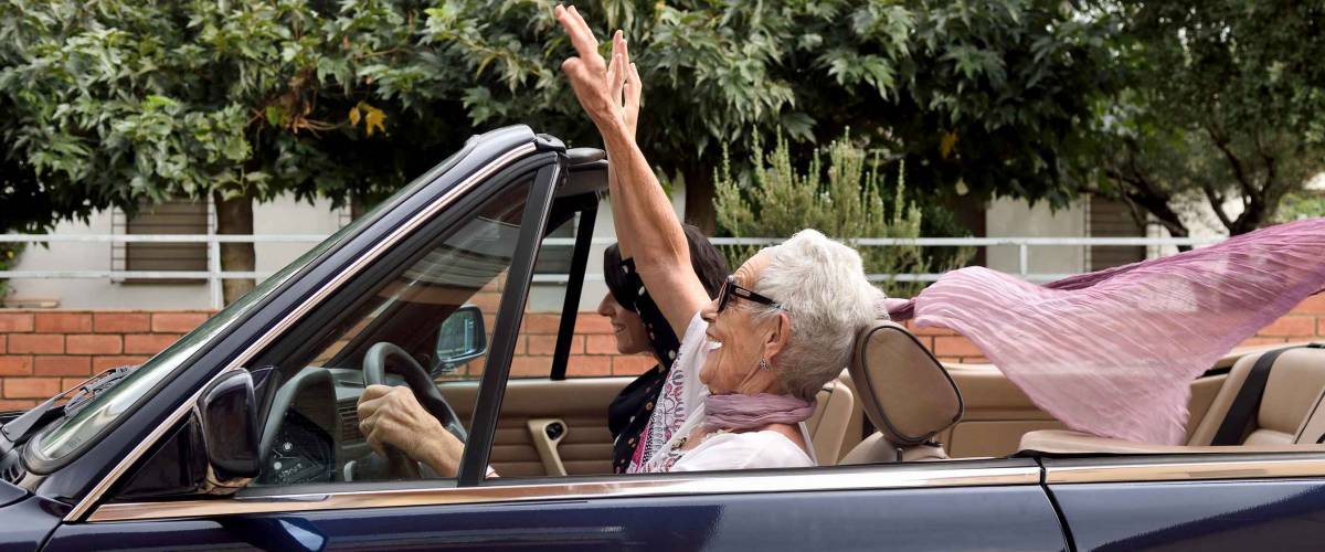 an older woman and a young woman driving a convertible