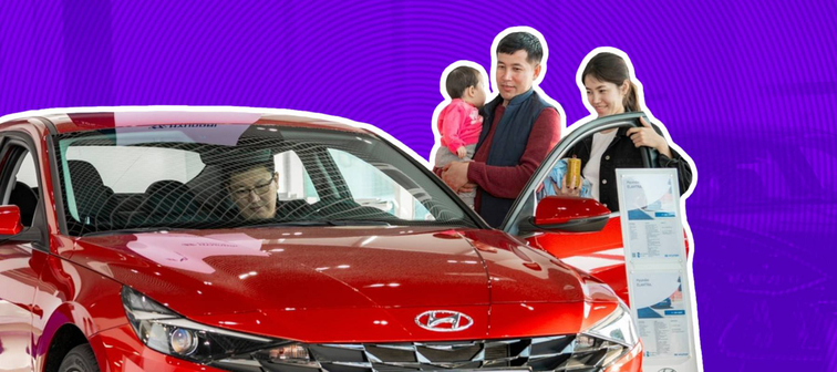Family looks at a bright red car on the dealership floor.