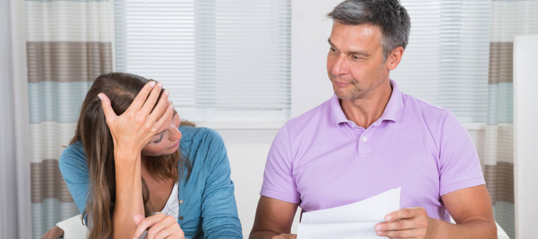 Worried Couple Looking At Unpaid Bills At Home.